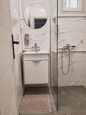 a white bathroom with a sink and a shower at Prenoćište Katarina JUGOVO in Smederevo