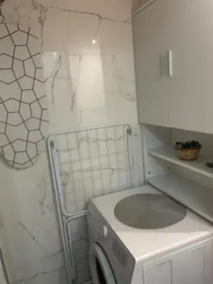 a bathroom with a washing machine in a white room at M&O Belgrade in Belgrade