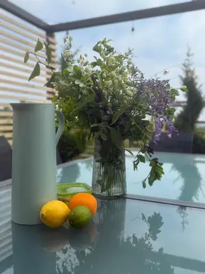 a vase with flowers and oranges on a glass table at Casa del Corniolo Spa and Pool House Fruška gora in Čortanovci