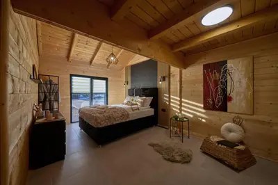 a bedroom with a bed in a room with wooden walls at Casa del Corniolo Spa and Pool House Fruška gora in Čortanovci