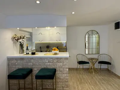 a kitchen with a bar with two chairs and a table at Apartman City Zeleznik in Belgrade