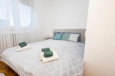 a bedroom with a white bed with two chairs on it at Apartment Sofia in Belgrade