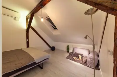 a attic bedroom with a bed and a couch at City Centre Rooftop Knez Mihailova Apartment in Belgrade