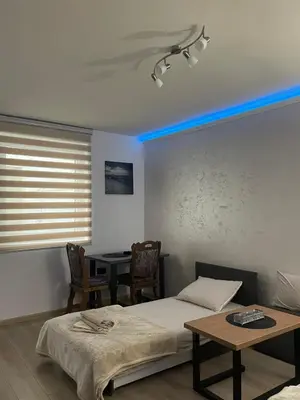 a room with two beds and a table and a blue light at Apartman Silver Bg in Kneževac