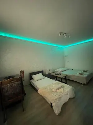 a room with two beds and a table and blue lights at Apartman Silver Bg in Kneževac
