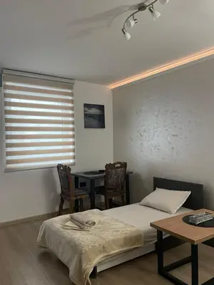a bedroom with a bed and a table and a window at Apartman Silver Bg in Kneževac