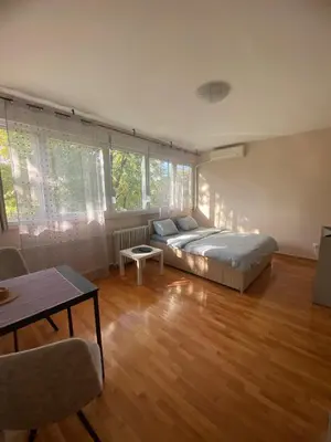 a bedroom with a bed and a table and some windows at Vist 3 apartment in Belgrade