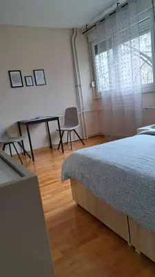 a bedroom with a bed and a table and a window at Vist 3 apartment in Belgrade
