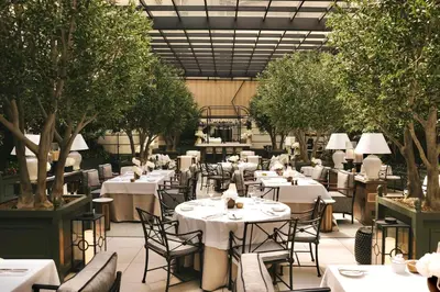 a restaurant with white tables and chairs and trees at The Bristol Belgrade in Belgrade
