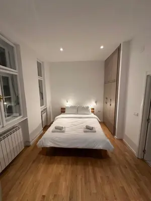 a large white bedroom with a large bed and wooden floors at City Centre Retreat Palmoticeva Studio in Belgrade