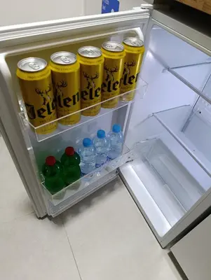 an open refrigerator with soda cans and bottles of water at Apartman Good Night in Surčin