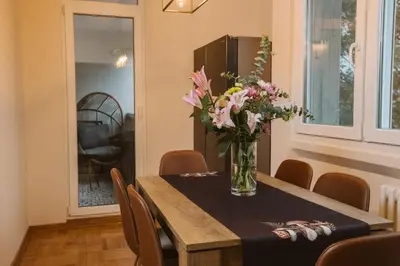a dining room table with a vase of flowers on it at Bright, Newly Renovated Condo Near Danube River in Belgrade