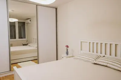 a bedroom with a white bed and a mirror at Bright, Newly Renovated Condo Near Danube River in Belgrade
