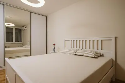 a bedroom with a large white bed and a bathroom at Bright, Newly Renovated Condo Near Danube River in Belgrade