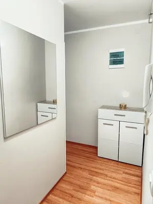 a kitchen with white cabinets and a mirror at Apartman Đul in Mladenovac