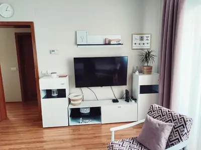 a living room with a white entertainment center with a television at Apartman Đul in Mladenovac