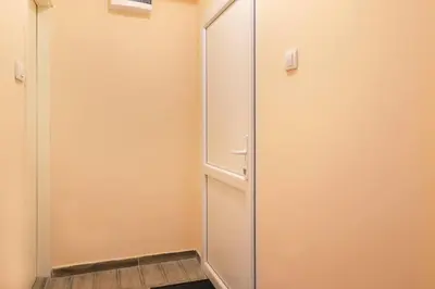 a glass shower door in a room with a wooden floor at Biser 17 in Zemun