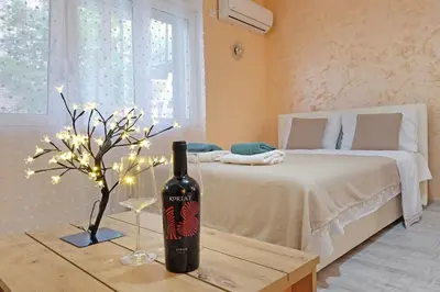 a bottle of wine on a table next to a bed at Biser 17 in Zemun