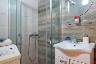 a bathroom with a shower and a sink and a mirror at Biser 17 in Zemun