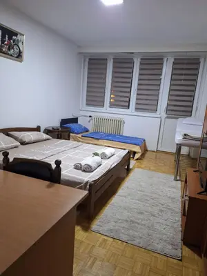 a room with three beds and a table and chairs at Relax apartman bg in Belgrade