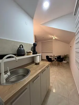 a kitchen with a sink and a dining table at Apartman Cristal LUX in Surčin