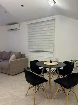 a living room with a table and chairs and a couch at Apartman Cristal LUX in Surčin