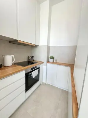 a kitchen with white cabinets and a black oven at West 65 airport city apartment in Belgrade