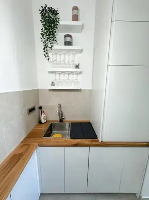 a small kitchen with white cabinets and a sink at West 65 airport city apartment in Belgrade