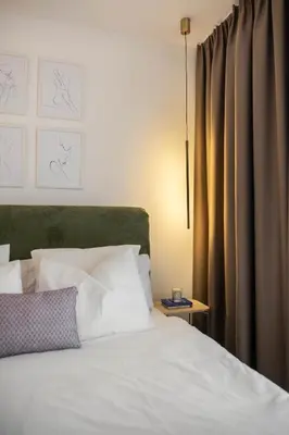 a bed with a green headboard and white pillows at Designer flat with character in Belgrade