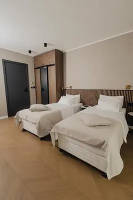two beds in a large room with wooden floors at Hotel Flaneur in Belgrade