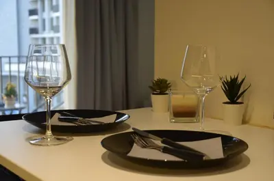 a table with two glasses and a plate and fork and knife at Waterfront Retreat with Garage and Balcony in Belgrade