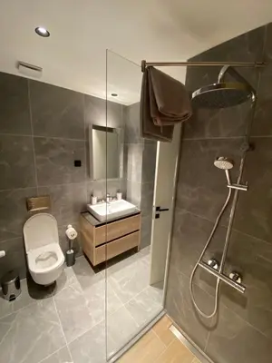a bathroom with a shower and a toilet and a sink at Waterfront Retreat with Garage and Balcony in Belgrade