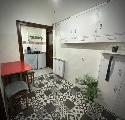a kitchen with a tile floor with a table and a refrigerator at Sunset apartment in Belgrade