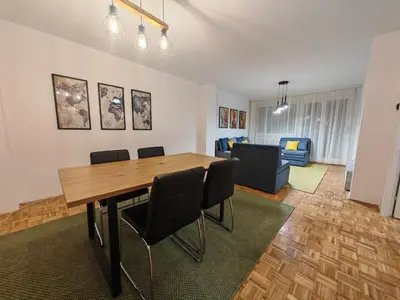 a dining room with a table and chairs and a living room at NEW BELGRADE Lovely three bedroom apartment in Belgrade