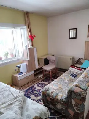 a room with two beds and a chair and a window at Home in flowers in Belgrade
