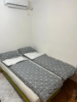 a bed in a room next to a wall at Aurora Apartmani Indjija in Inđija