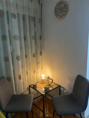 a room with two chairs and a table with a clock at Aurora Apartmani Indjija in Inđija