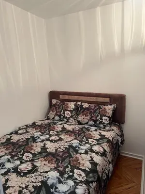 a bed with a floral comforter in a bedroom at Aurora Apartmani Indjija in Inđija