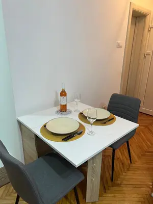 a white table with two glasses and a bottle of wine at Aurora Apartmani Indjija in Inđija
