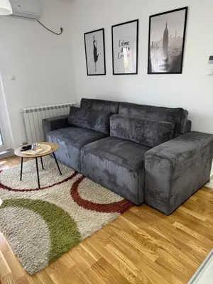 a living room with a black couch and a table at Apartman Pazova in Stara Pazova