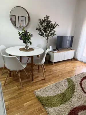 a dining room with a table and chairs and a tv at Apartman Pazova in Stara Pazova