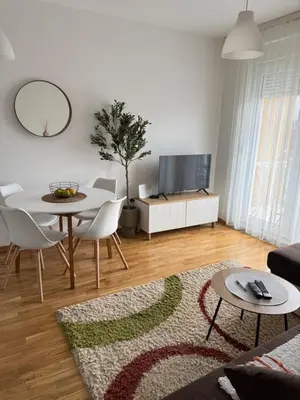 a living room with a table and a tv at Apartman Pazova in Stara Pazova