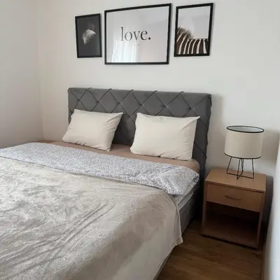 a bed in a bedroom with pictures on the wall at Apartman Pazova in Stara Pazova