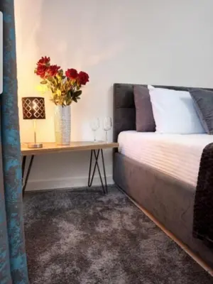 a bed and a table with a vase of flowers at Rose City Centre Apartment in Belgrade