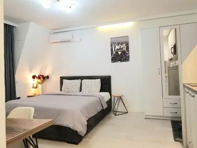 a bedroom with a large bed and a table at Rose City Centre Apartment in Belgrade
