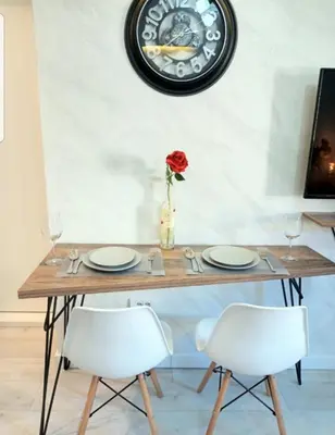 a table with two chairs and a clock on the wall at Rose City Centre Apartment in Belgrade