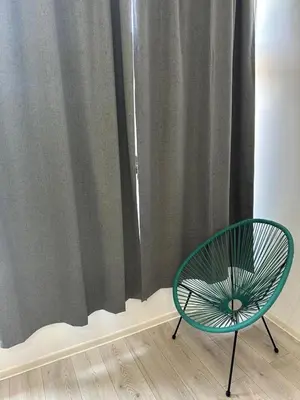 a green chair sitting in front of a curtain at lovely studio apartment in Belgrade