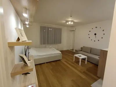 a bedroom with a bed and a couch and a clock on the wall at Stela apartment in Belgrade