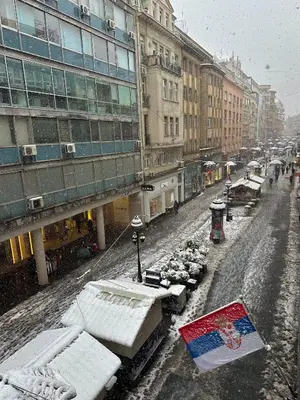 a snow covered city street with buildings and cars at The Horse Monument Hostel in Belgrade
