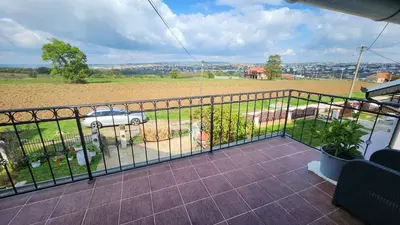 a balcony with a fence and a car in a field at Sobe i apartmani Djordjevic in Mladenovac